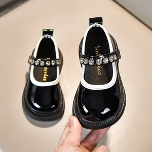 Details von schwarzen Lack-Mary-Janes für Mädchen mit Strassriemen und weißer Einfassung