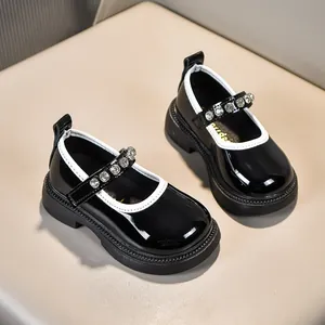 Detailaufnahme der glänzenden schwarzen Lacklederschuhe für Mädchen mit Strasssteinen und Gummisohle