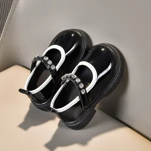Detail von Mädchen Mary Janes aus schwarzem Lackleder mit Kristallbesatz und dicker Sohle
