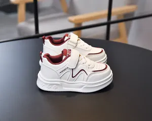 Detail view of burgundy leather accents and breathable holes on white kids sneakers
