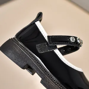 Nahaufnahme schwarzer Lackleder-Mary-Janes mit Strasssteinen und dicker Gummisohle