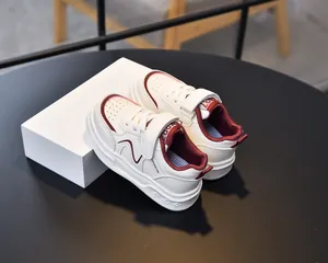 Detail view of breathable white and burgundy kids sneakers with velcro strap and sport logo