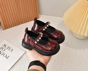 Detalle de zapato Mary Jane para niña en charol burdeos con hebilla de strass y suela de goma