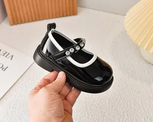 Vista macro de zapatos Mary Jane en charol negro con pedrería y borde blanco