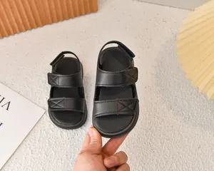 Dettaglio di sandali neri da bambino con cinturini a punto croce e chiusura in velcro