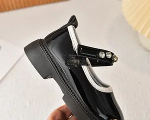 Detalle de zapatos de charol para niña con hebillas de diamantes y bordes en contraste