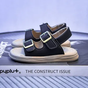 Detail of kids black leather sandals with golden buckles on a stylish platform sole