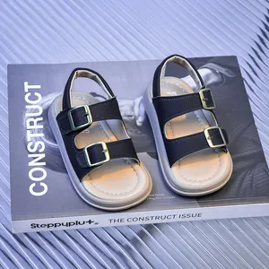 Close-up of black double-buckle sandals for toddlers with gold hardware on a book