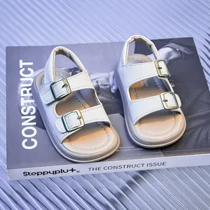 Macro detail of white double-strap sandals with golden buckles on a magazine background