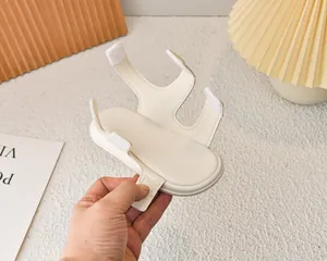 Dettaglio dei cinturini in velcro color crema e supporto ovale per sandali da bambino o passeggini