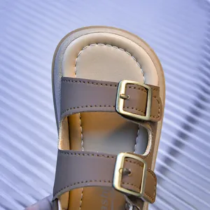 Detailed macro view of children's brown cork sandals with gold buckles and white stitching