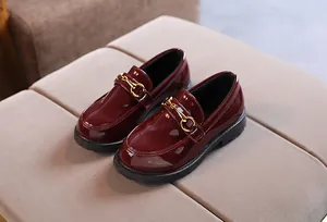 Detailed macro view of dark burgundy patent leather children's loafers with gold horsebit
