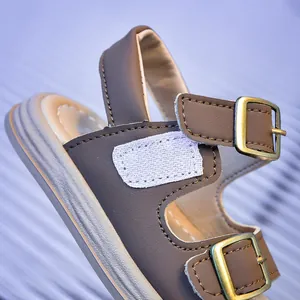 Close-up of brown kid's sandal featuring adjustable metal buckle and hook-and-loop strap