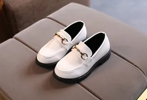 Detail of white glossy children's loafers with gold metal horsebit and black rubber soles