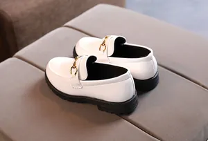 Detailed macro view of white patent leather loafers with classic gold horsebit buckle