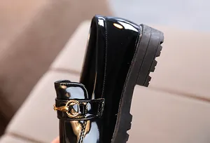 Detail of kids black patent leather loafers with golden horsebit and lugged rubber sole