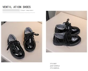 Détail de chaussures enfant en cuir verni noir avec broderie brogue et design à lacets