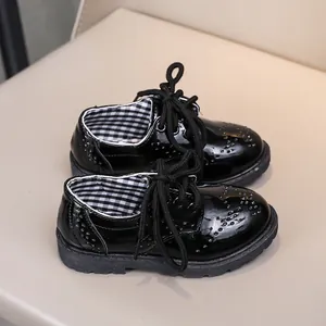 Gros plan de chaussures brogues en cuir verni noir pour enfants avec détails perforés