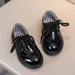 Détail de chaussures brogues en cuir verni noir pour enfants avec motifs perforés