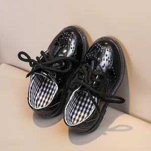 Détails macro des chaussures richelieu en cuir verni noir pour enfants à perforations