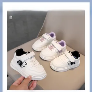 Detail of kids white leather sneakers with 3D cartoon bear decor and velcro strap