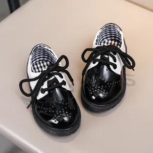 Détail de chaussures Richelieu pour enfants en cuir verni noir et blanc avec perforations