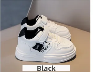 Detailed side view of white children's sneakers with black bear motif and velcro straps