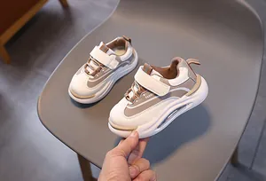 Dettaglio di sneaker per bambini bianche e marroni con velcro e suola spessa