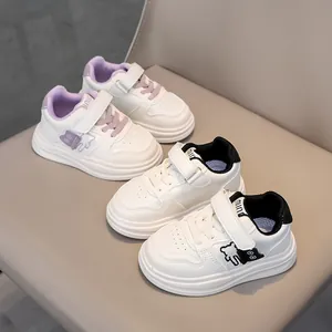 Detail view of children's white sneakers with soft sole and cute bear pattern on side
