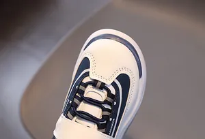 Dettaglio scarpe sportive bimbo con cinturino in velcro e punta rotonda in pelle bianca