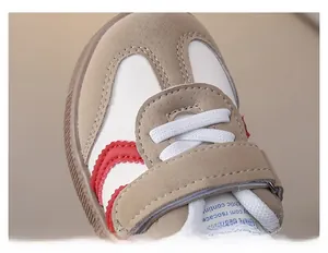 Macro detail of toddler sneakers featuring beige synthetic leather and red wave pattern