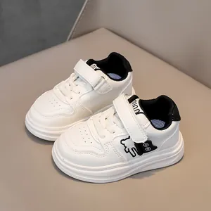Detail of white leather kids sneakers with bear motif and velcro strap closure