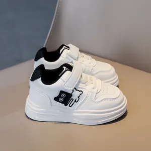 Detail of white kids sneakers with cute black bear embroidery and velcro straps