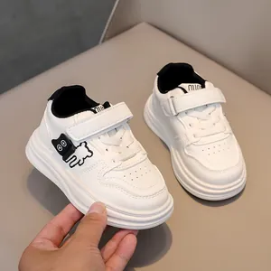 Detail of white kids sneakers with bear embroidery and adjustable velcro straps