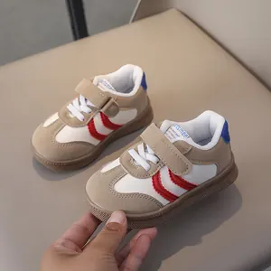 Close-up of beige boys' sneakers featuring red wavy stitching and velcro strap details