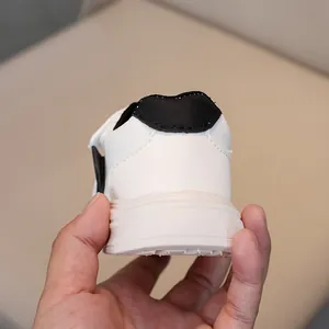 Detail shot of children's white leather sneakers featuring black heel tab and rubber sole