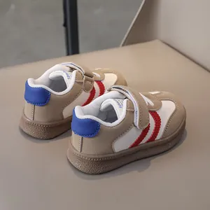 Detail view of beige and white leather kids sneakers with red waves and non-slip rubber soles
