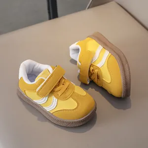 Top view of yellow leather kids sneakers with hook and loop strap and rubber sole