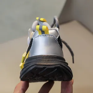 Detail of kids sports shoe heel with silver metallic finish and yellow pull tab