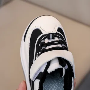 Dettaglio scarpe sportive bimbi con chiusura in velcro e trama in pelle bicolore