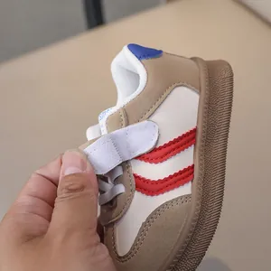 Detail of children's vintage sneakers with red stripes, Velcro strap and gum sole
