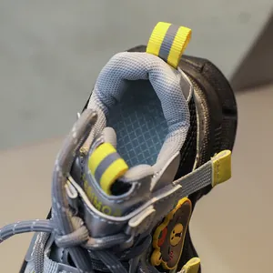 Detail of children's grey mesh sneaker featuring yellow heel pull tab and soft padding