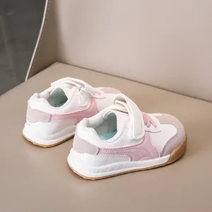 Detail view of pink and white kids' sneakers with hook and loop closure on beige leather