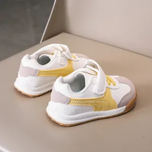 Detail of children's white sports sneakers with yellow stripes and velcro strap closure