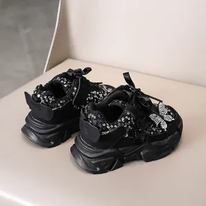 Détail de chaussures noires à paillettes pour filles avec nœuds satinés et strass brillants