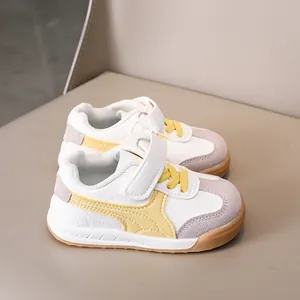 Close-up of children's sneaker with white leather, grey suede and yellow stripes
