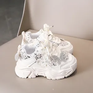 Détail de baskets blanches pour filles avec paillettes, fleurs en dentelle et nœud en strass