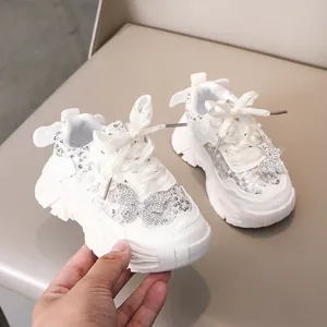 Détail de baskets blanches pailletées pour filles avec papillon strass et lacets en satin