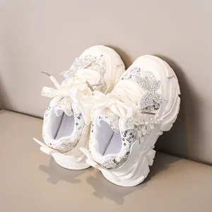 Détail de baskets blanches pour filles avec paillettes argentées et nœud en soie