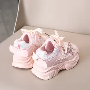 Détail de chaussures roses pour fillettes avec paillettes, papillons strass et lacets soie